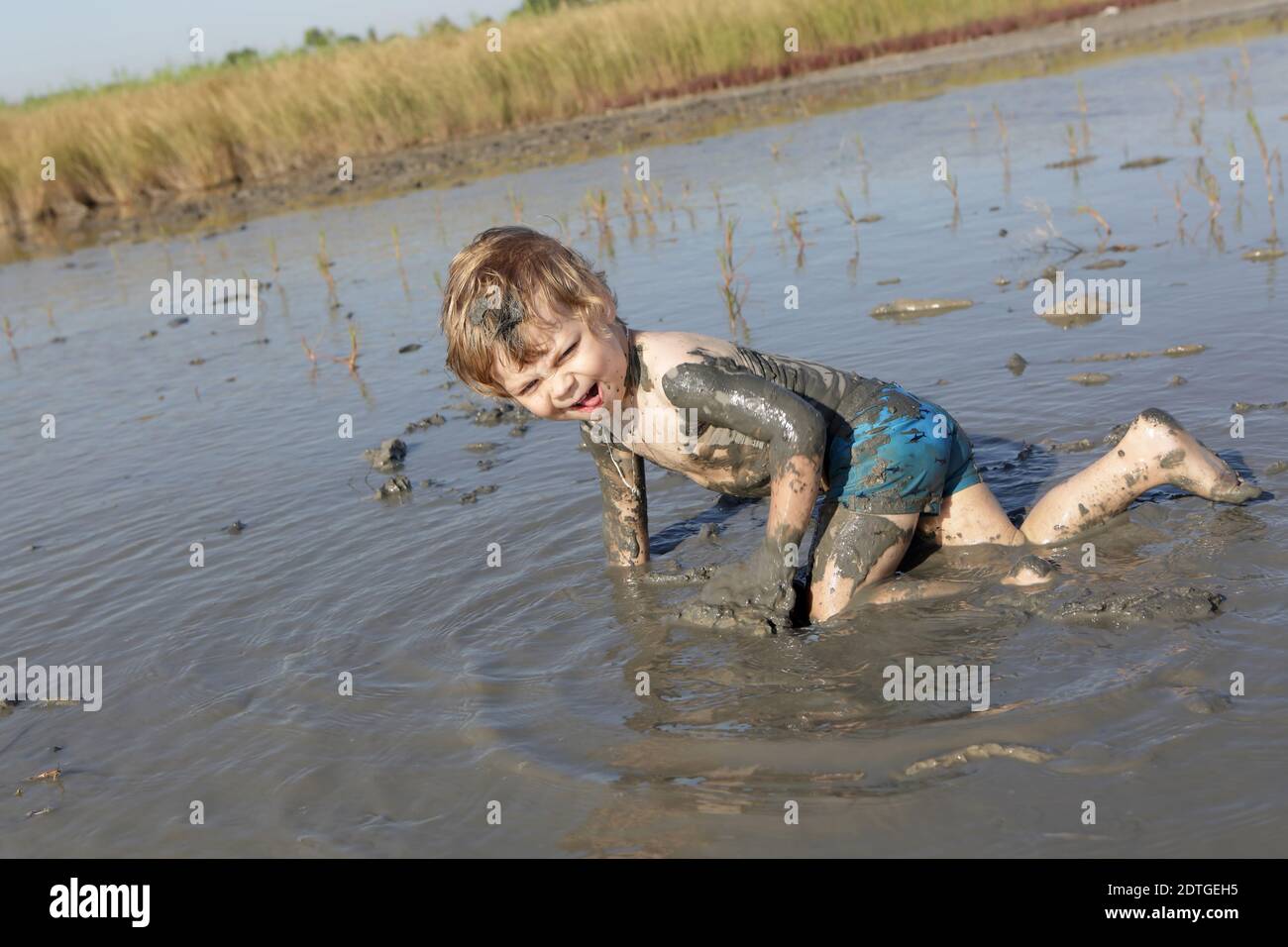 El niño está arrastrándose en barro curativo, Rusia Foto de stock