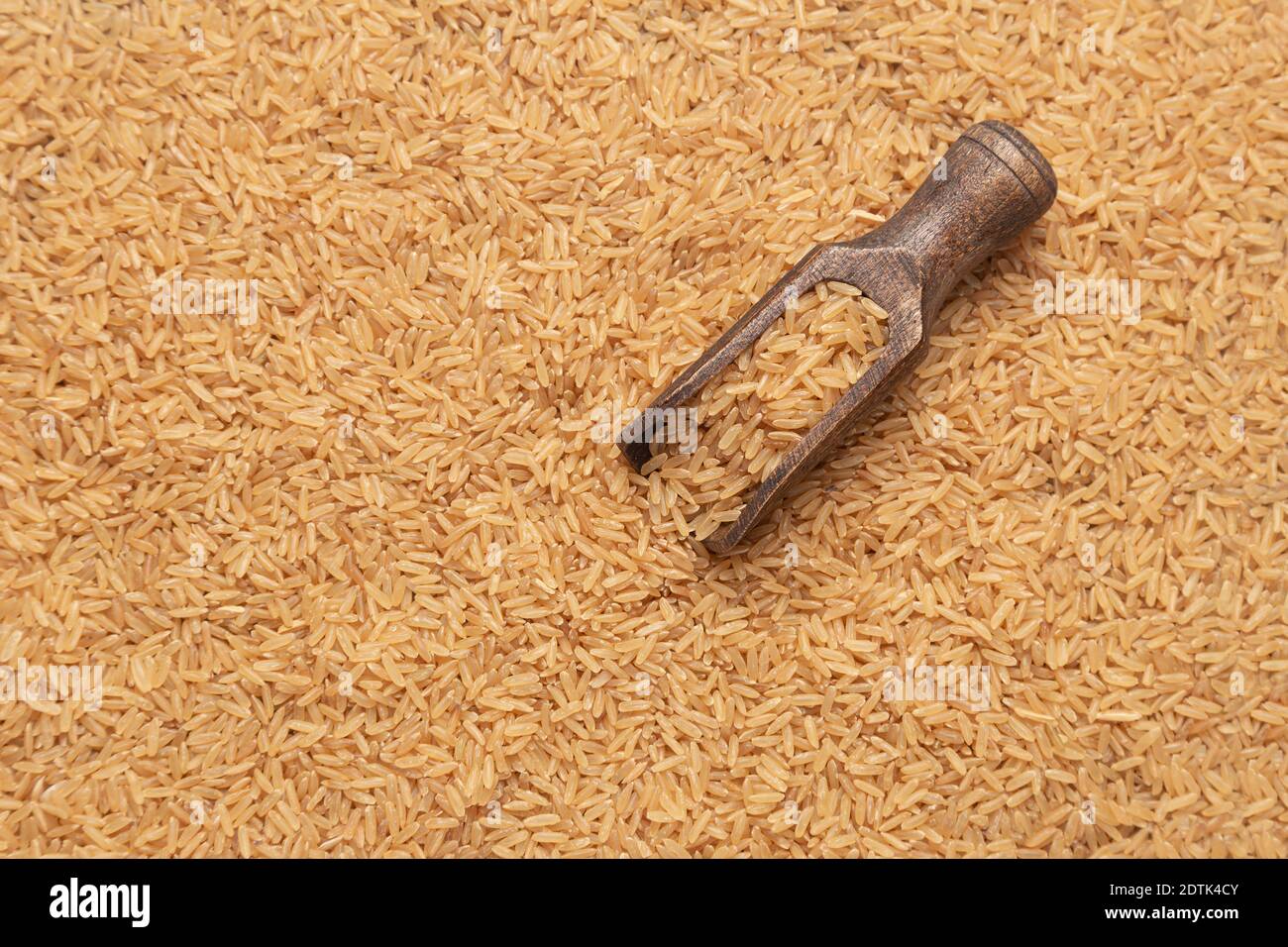 cuchara de madera con arroz marrón sobre fondo de arroz marrón. Foto de stock