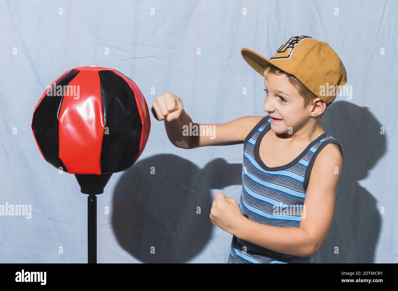 Un niño caucásico golpeando en una bolsa de boxeo con puños Foto de stock