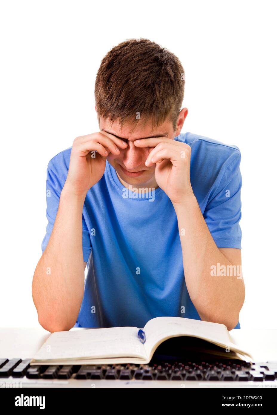 Estudiante cansado frotar los ojos en el Escritorio de la Escuela aislado Sobre el fondo blanco Foto de stock