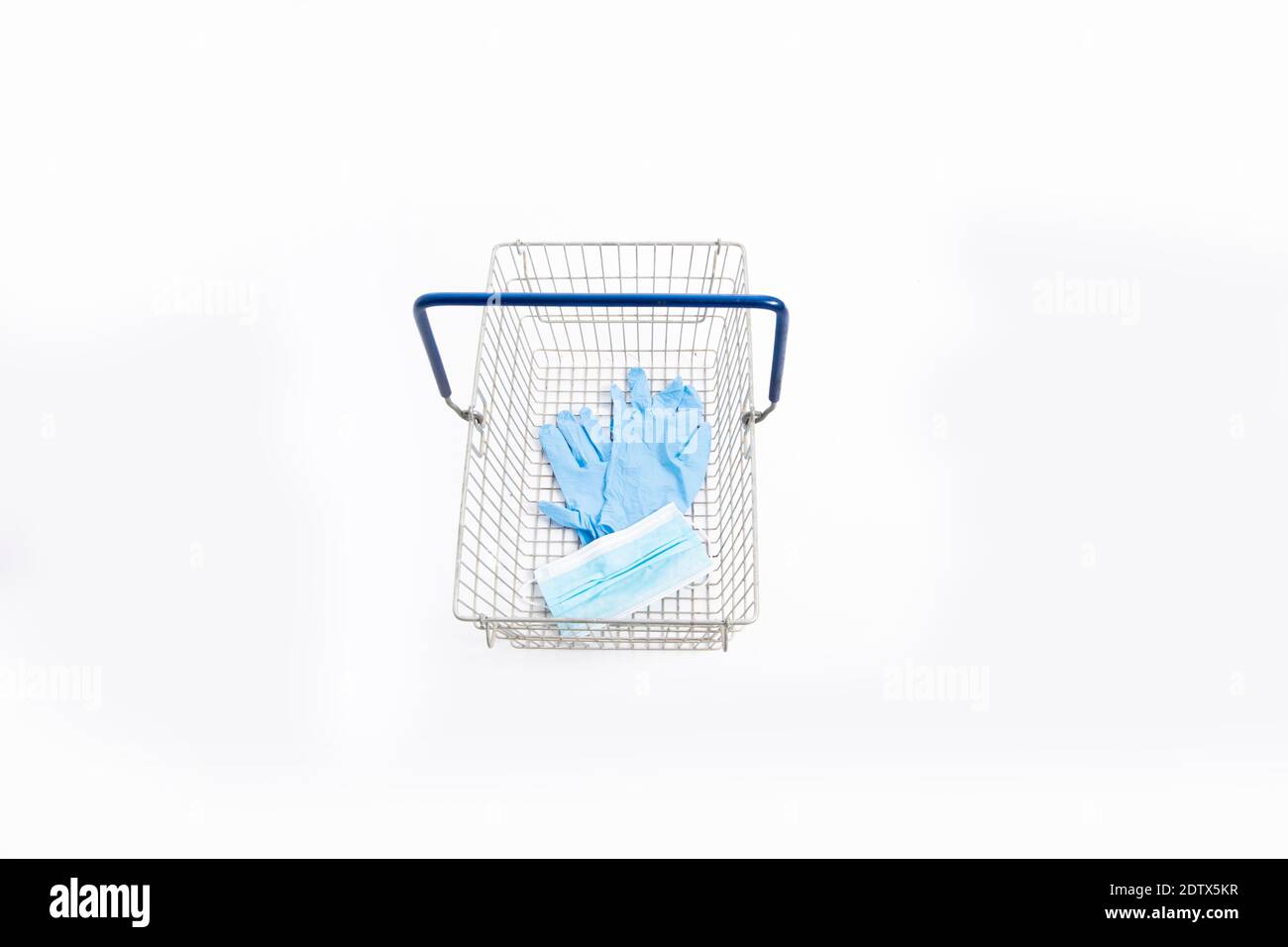Cesta de la compra con guantes de mano y mascarilla, aislada sobre fondo blanco Foto de stock