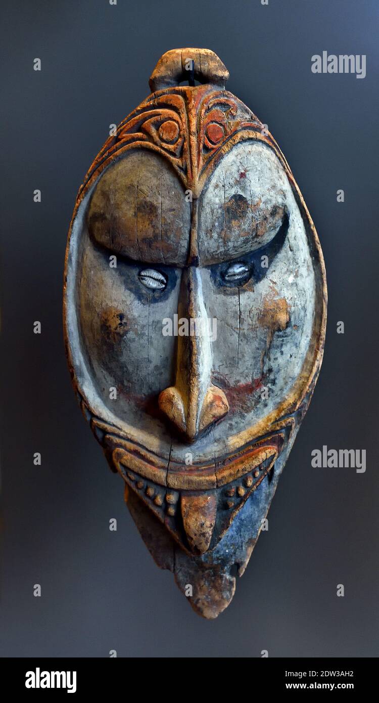 Una máscara plana de madera se adjuntó a la pared en una casa de hombres, (madera, pintura, concha, pelo, dientes de cerdo,) Sepik cuenca, Papua Nueva Guinea principios del siglo 20 Papúa, Nueva Guinea, Indonesia Foto de stock