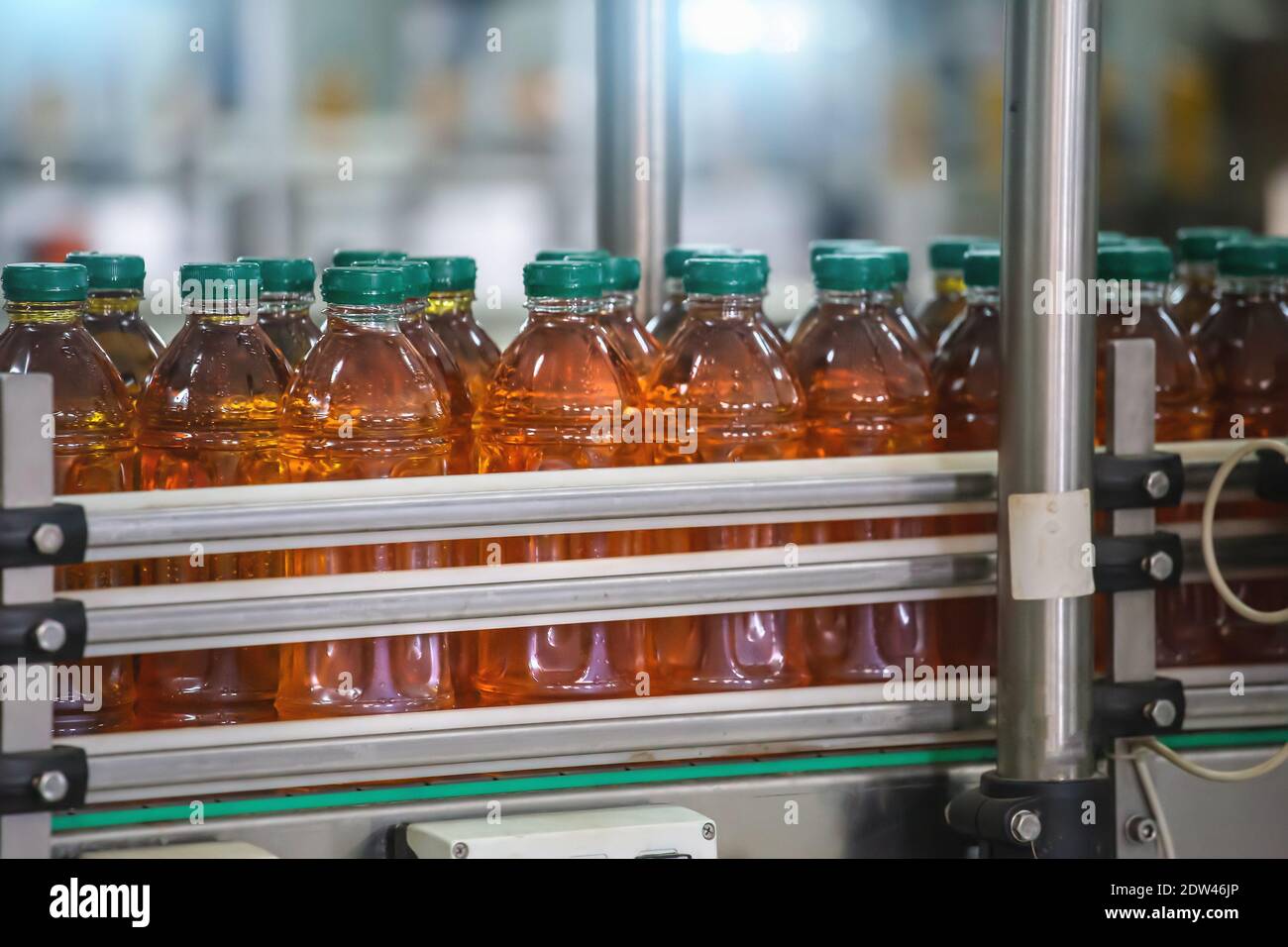 Botellas de la línea transportadora con jugo. Producción industrial de la industria alimentaria de bebidas. Foto de stock