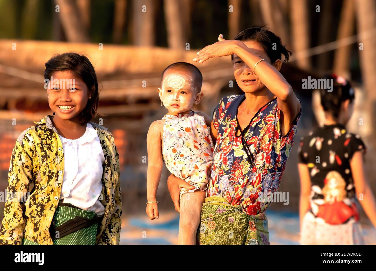 En el pueblo pesquero de Jade Taw, Myanmar, tres generaciones de mujeres observan a sus hombres navegando hasta la puesta de sol. La pesca aquí se hace por la noche. Foto de stock