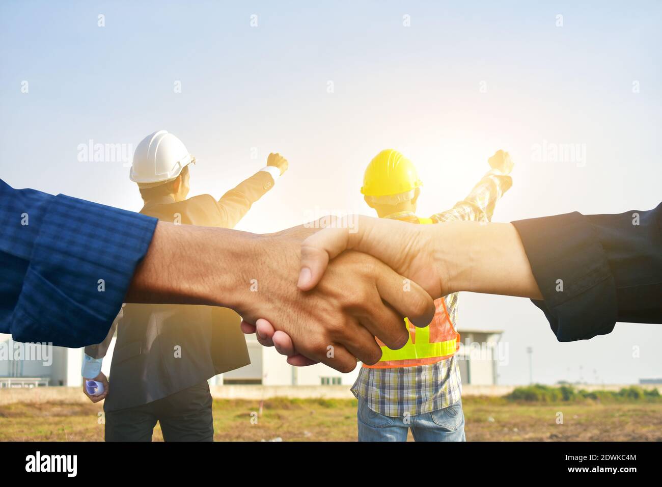 La gente de negocios se sacude las manos y el ingeniero que sostiene el proyecto de éxito de la mano antecedentes de fábrica Foto de stock