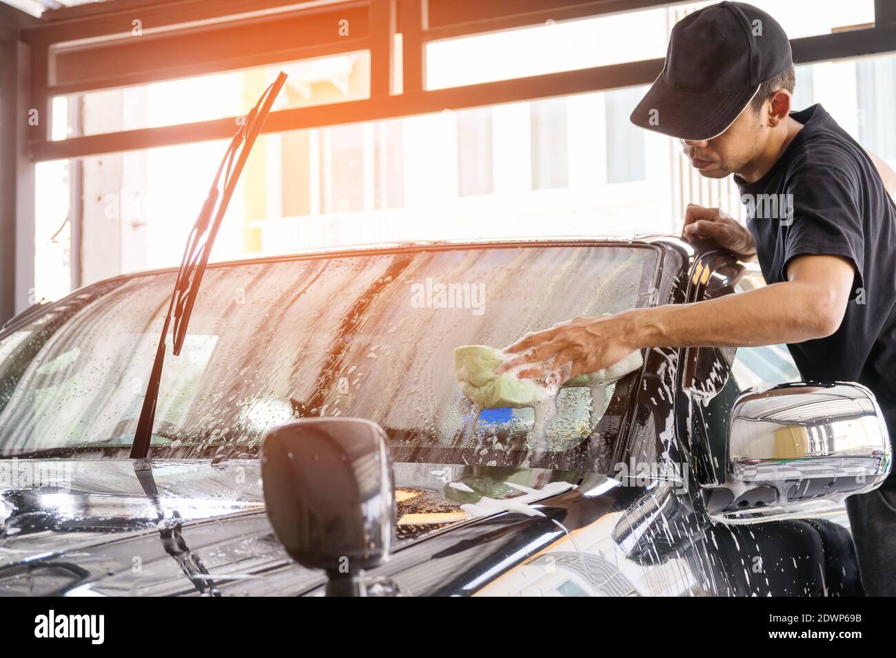 El trabajador de lavado de coches que lleva una camiseta y una gorra negra  está utilizando una esponja para limpiar el coche en el centro de lavado de  coches, concepto para la industria del cuidado de coches Fotografía de  stock - Alamy