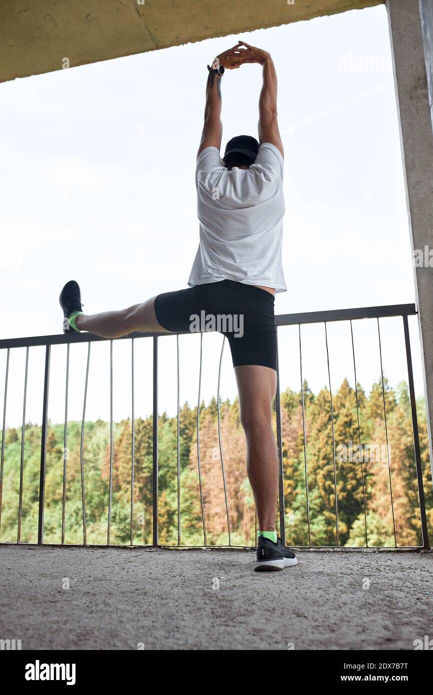 Atleta masculino concentrado corriendo por las escaleras para hacer el entrenamiento más intensivo. Deportivo hermoso joven hombre entrenando solo al aire libre. Escalera de entrenamiento conc Foto de stock