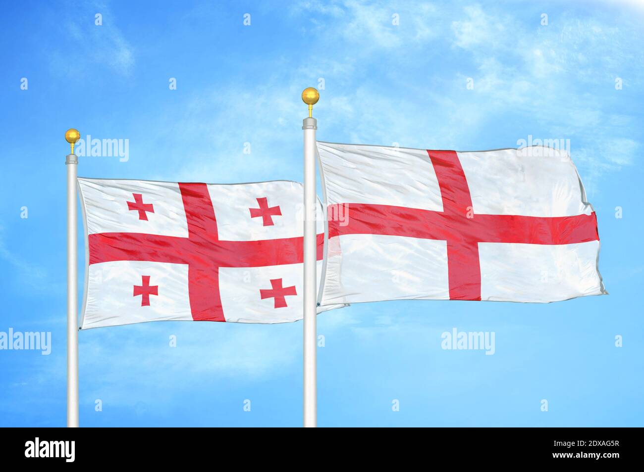 Georgia e Inglaterra dos banderas en los postes de la bandera y el cielo azul Foto de stock