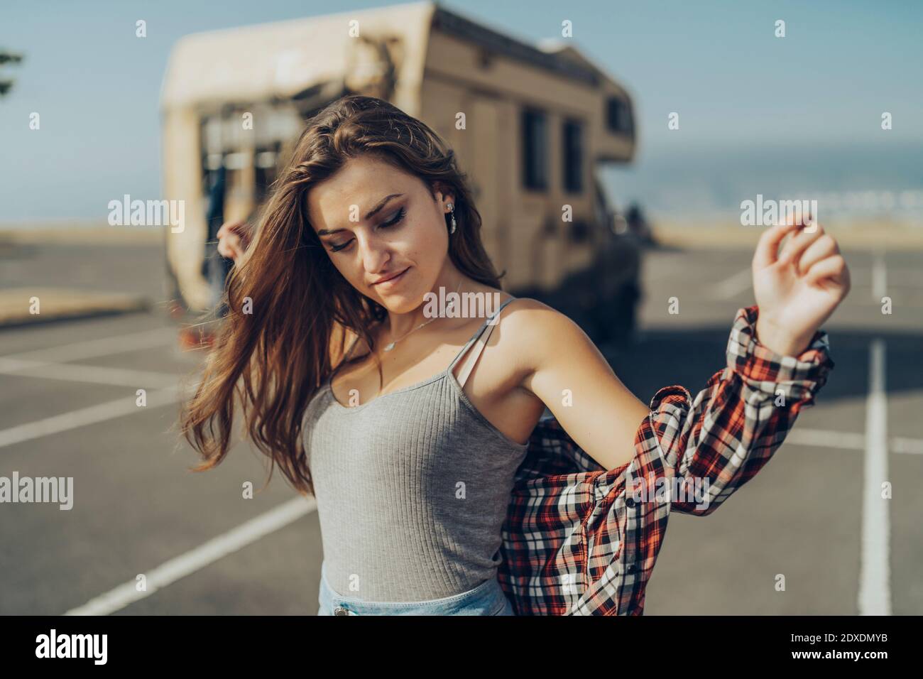 Mujer joven con los brazos estirados de pie en la carretera Foto de stock