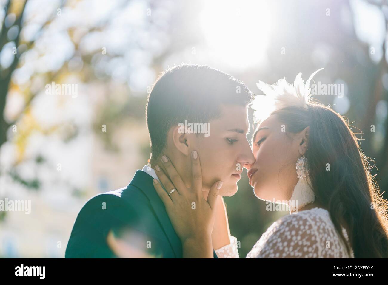 Una joven pareja casada besos en el parque el día soleado Foto de stock