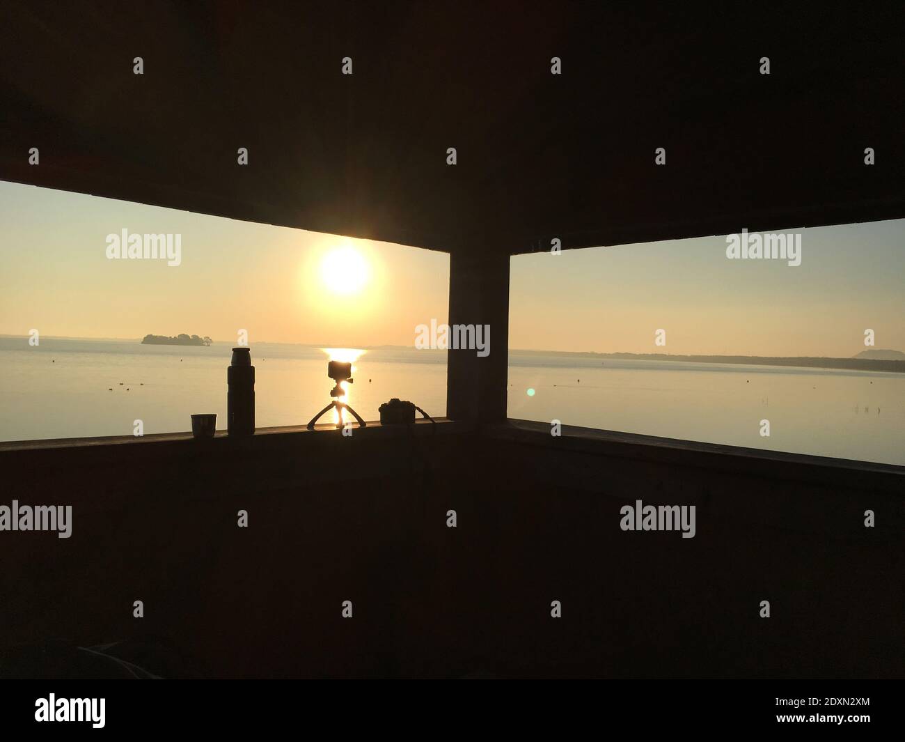 Cámaras Silhouette en el umbral de la ventana contra el mar durante la puesta de sol Foto de stock