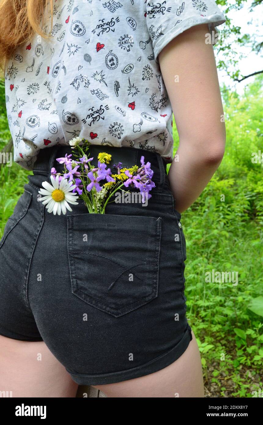 Parte media de la mujer con flores en el bolsillo del pantalón corto  Fotografía de stock - Alamy