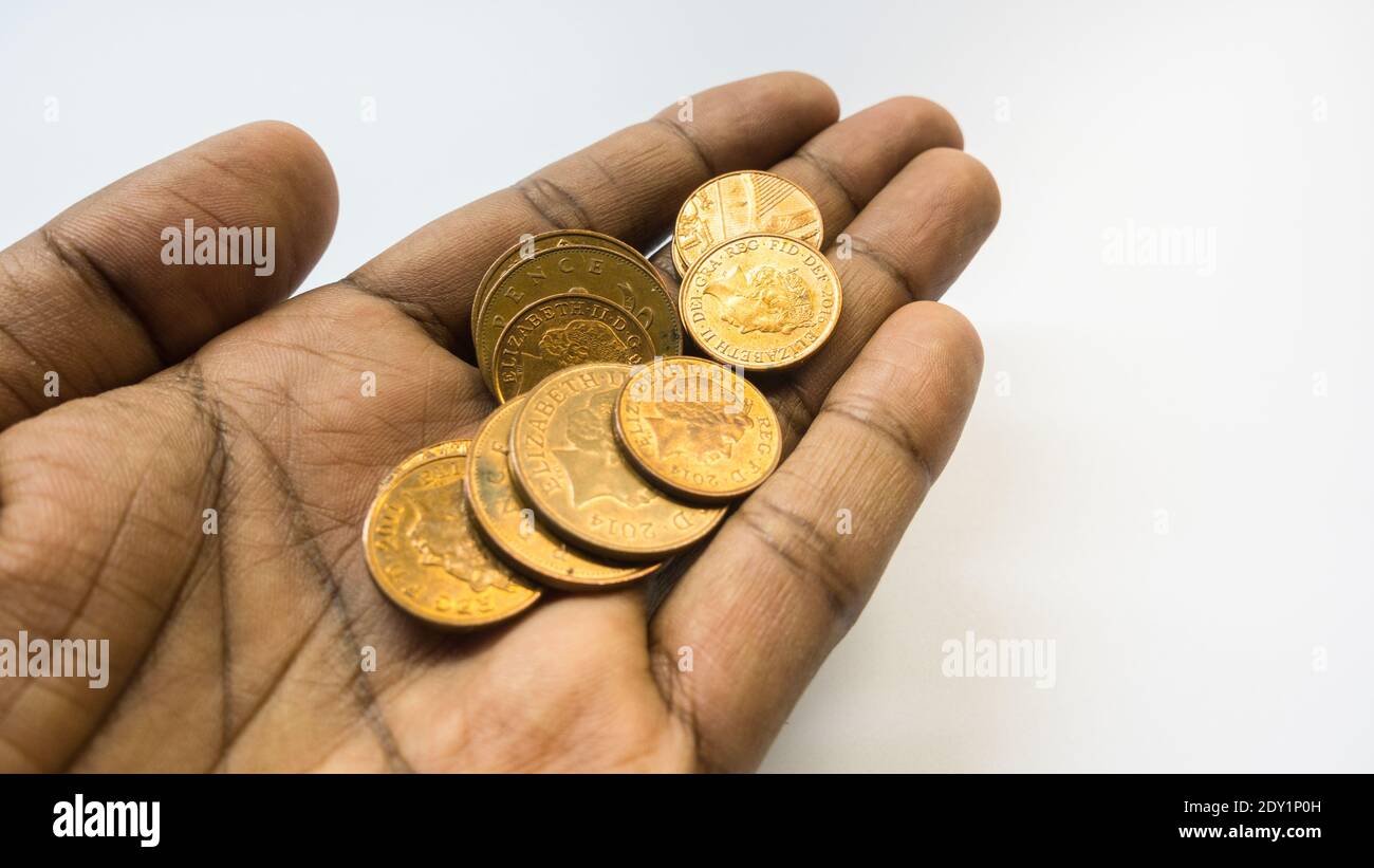 Hombre asiático manos con un puñado de monedas de penique Foto de stock