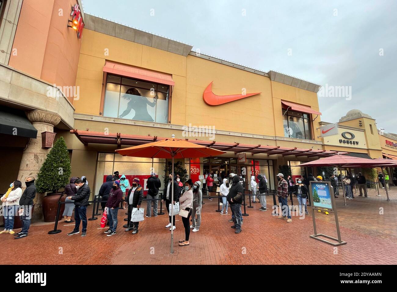 La gente se encuentra en línea fuera de la Marca True Religion Jeans, H&M y Nike tiendas el día antes de Navidad en el Citadel en medio de la coronav global