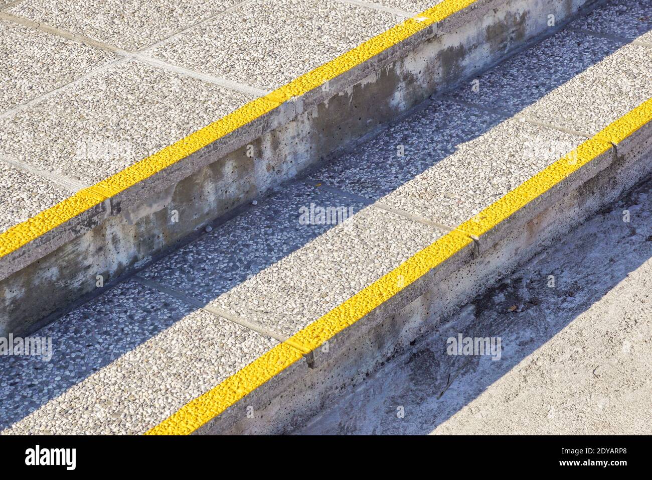 Línea amarilla en la acera con una escalera de hormigón curva Foto de stock