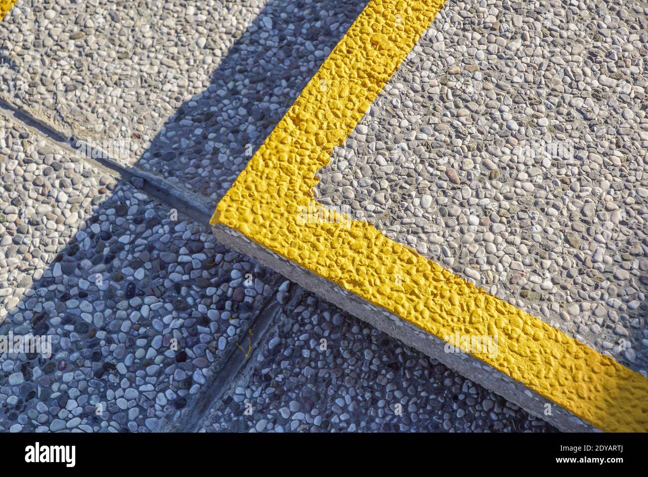 Línea amarilla en la acera con una esquina de piedra de toque de hormigón Foto de stock