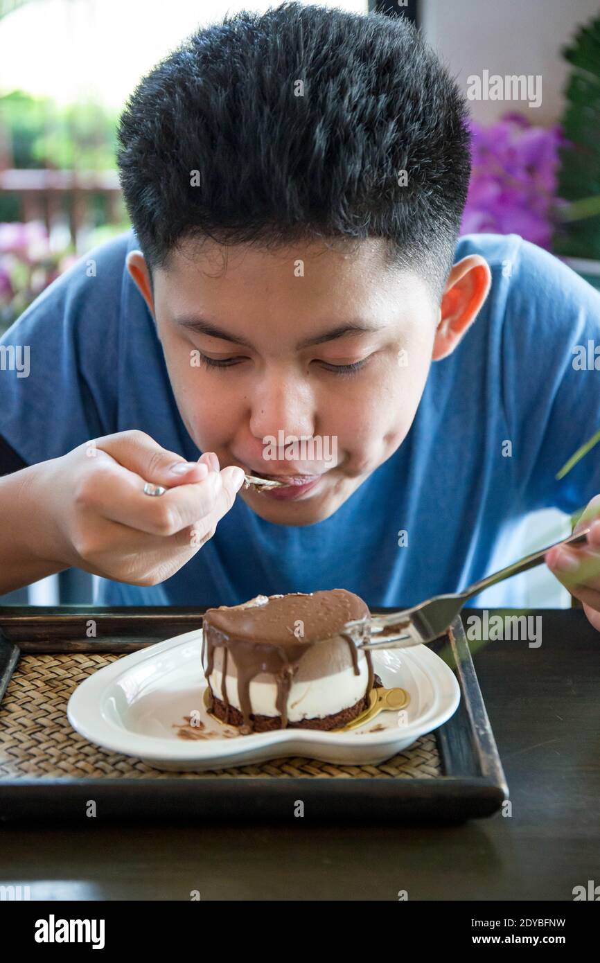 Niño comiendo pastel mientras está sentado en el Café Fotografía de stock -  Alamy