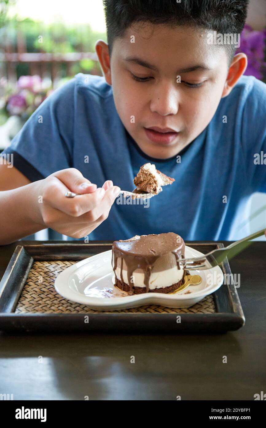Niño comiendo pastel mientras está sentado en el Café Fotografía de stock -  Alamy