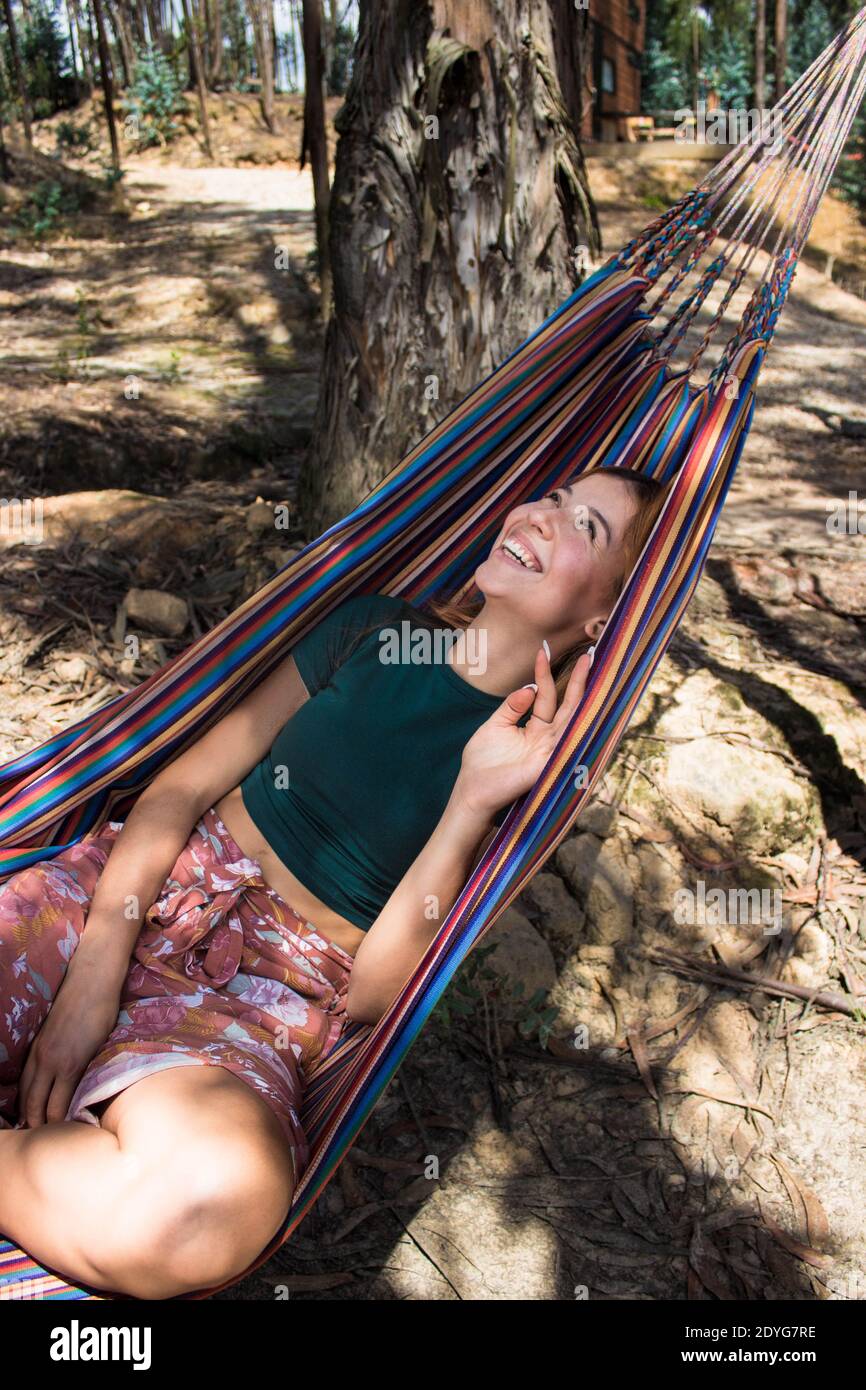 Una mujer positiva y sonriente acostada en una colorida hamaca y posando en  el patio en un día soleado Fotografía de stock - Alamy