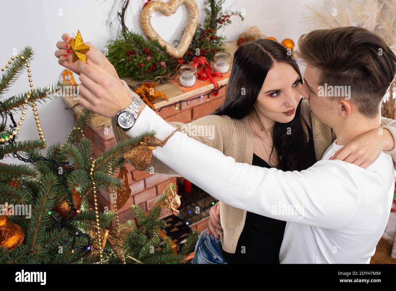 La novia y el novio seguirán decorando el árbol de Navidad. Decoración de  un árbol de Navidad para Navidad en diciembre Fotografía de stock - Alamy