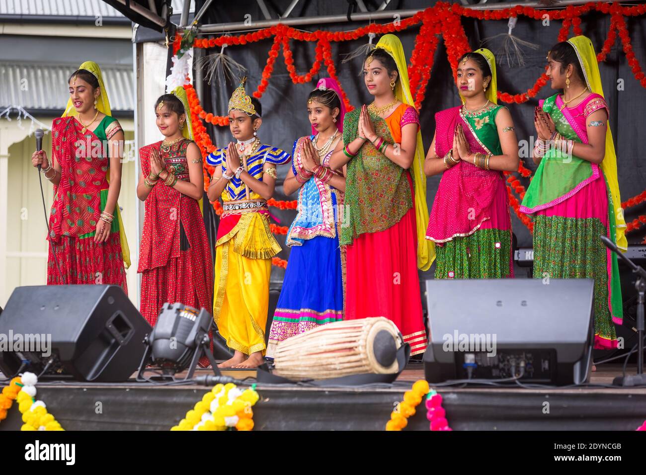 Una fila de mujeres indias en saris coloridos haciendo el gesto de namaste. Fotografiado en las celebraciones del festival de Diwali Foto de stock