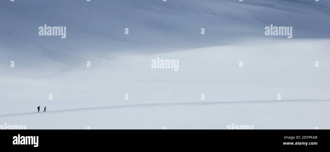 Dos personas en la nieve con un largo camino ir en un paisaje muy solitario Foto de stock