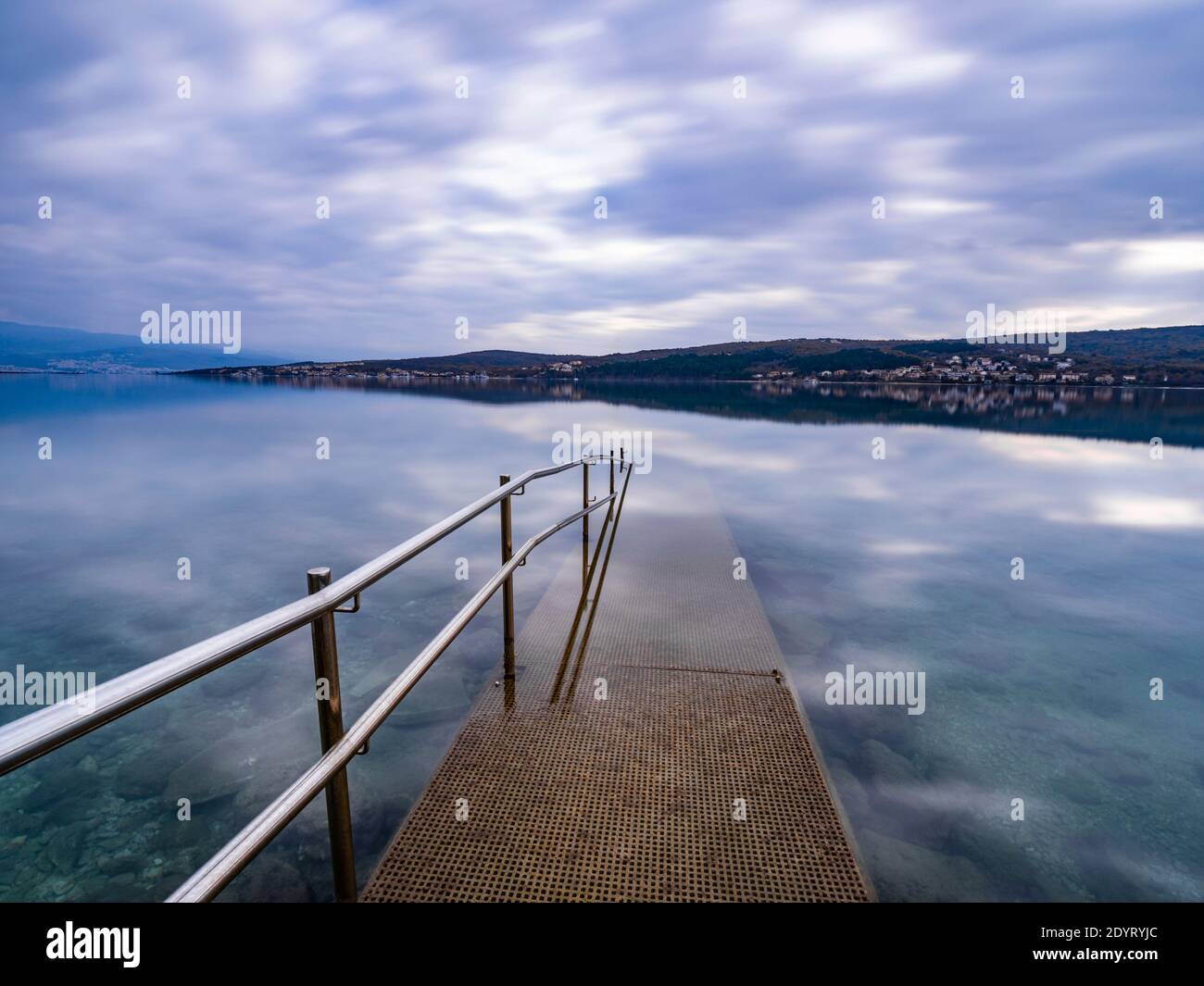 Barandilla de la valla metálica que conduce al mar de exposición larga Cizici En la isla de Krk en Croacia Europa la exposición prolongada refleja suave calma superficie calma Foto de stock