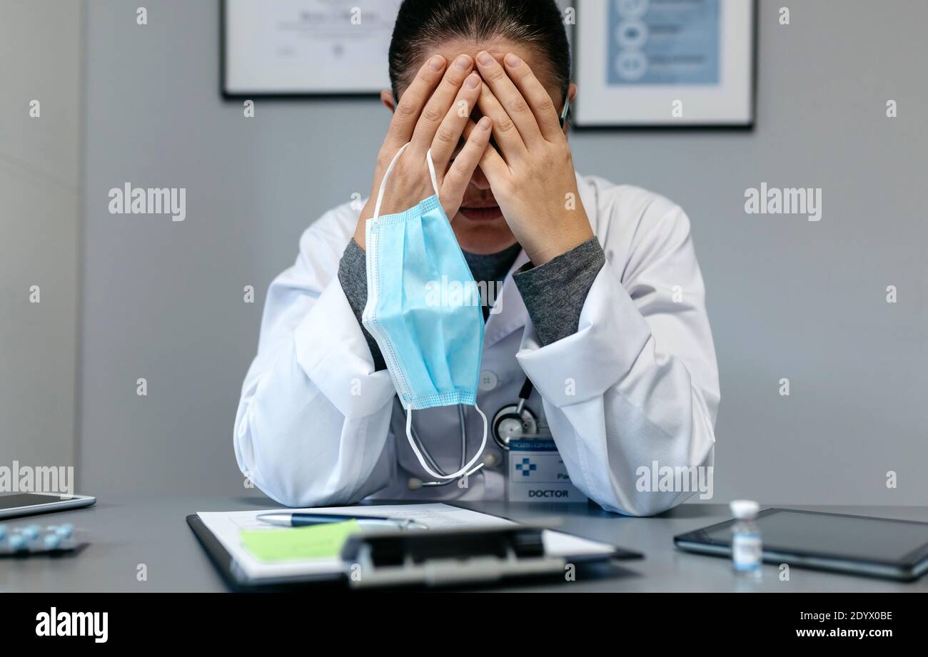 Doctor femenino con fatiga pandémica que cubre su cara Foto de stock