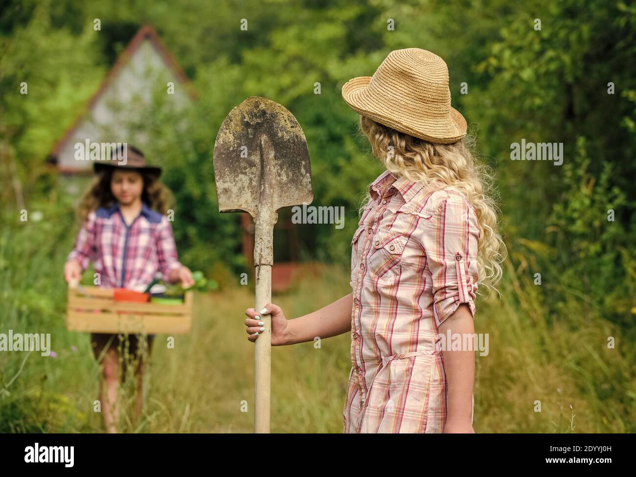 Niñas con herramientas de jardinería. Verano en el campo. Hermanas ayudando  en el patio trasero. Las herramientas de jardín aptas para los niños  garantizan la seguridad del jardinero infantil. Conceptos básicos de