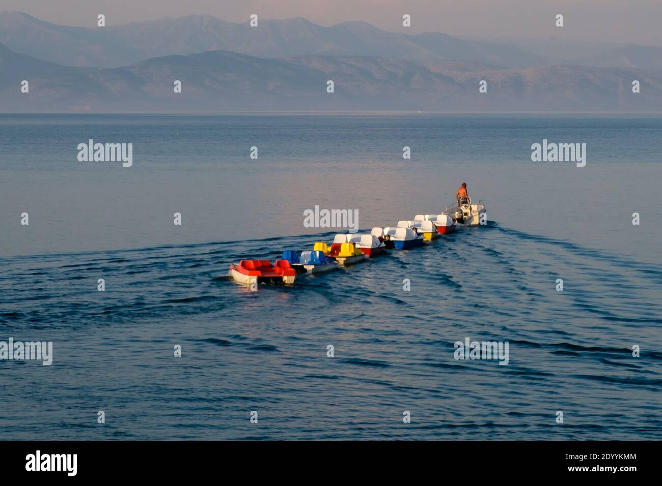 Un hombre en un barco está tirando una línea de catamaranes coloridos Foto de stock