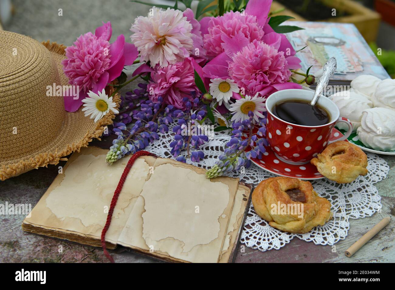 Todavía la vida con libro de diario abierto, manojo de flores, copa y sombrero en la mesa. Fondo botánico vintage con plantas, casa hobby todavía la con gar Fotografía de -
