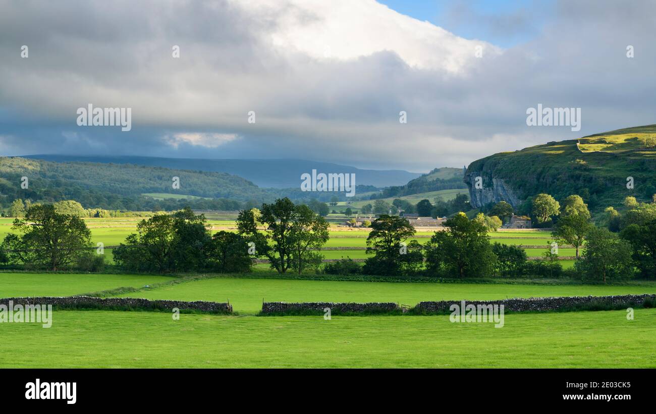 Valle de Wharfe (campos iluminados por el sol, paredes de piedra, Kilnsey Crag - alto acantilado de piedra caliza, colinas onduladas) - Wharfedale, Yorkshire Dales, Inglaterra, Reino Unido. Foto de stock