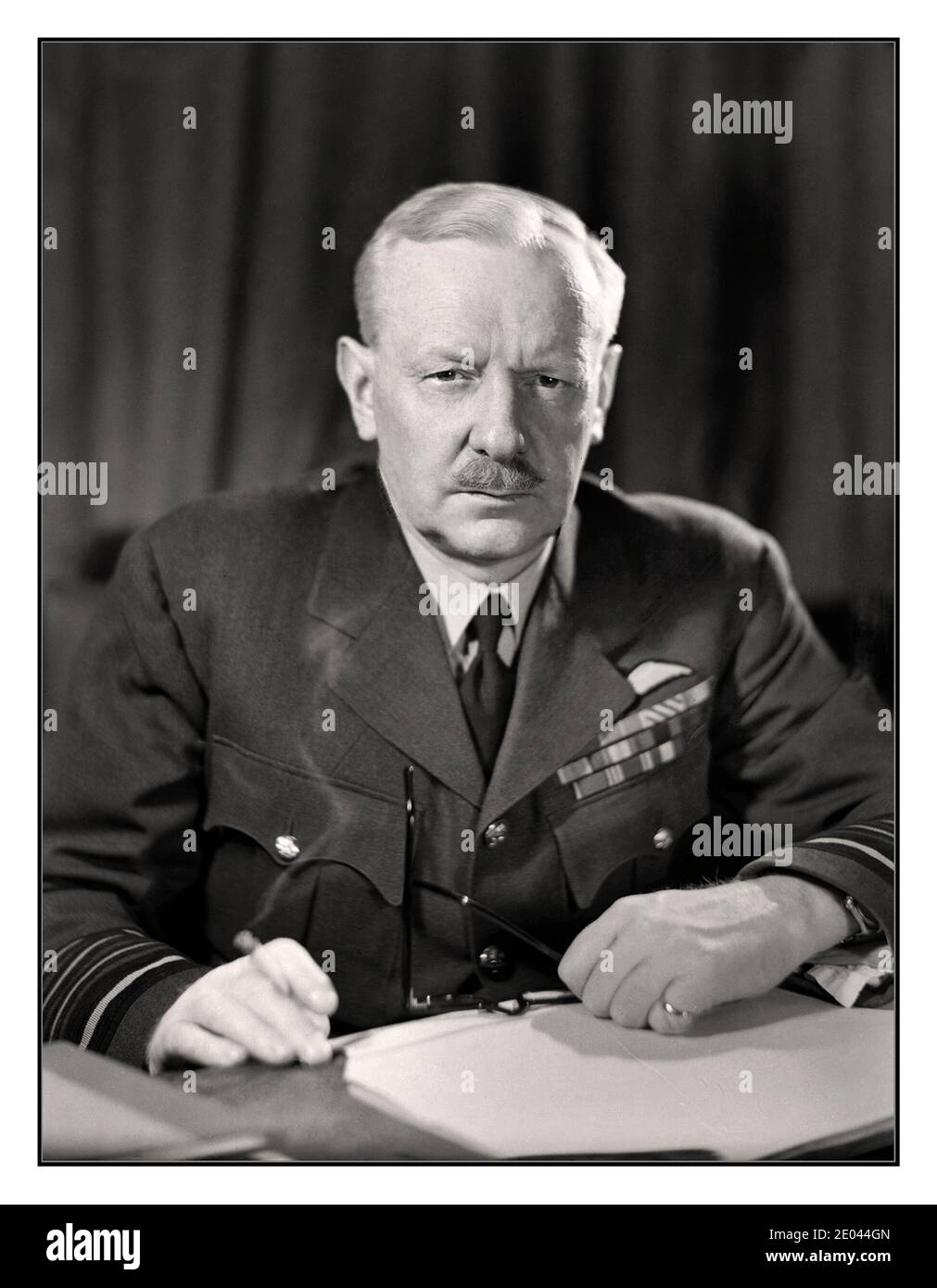 BOMBER HARRIS ARCHIVO Retrato Mariscal Jefe de Aire Sir Arthur Harris, Comandante en Jefe del comando de Bomber de la Fuerza Aérea Real, apodado ‘Bomber Harris” sentado en su escritorio, fumando un cigarrillo en el cuartel general del comando Bomber, High Wycombe. 24 de abril de 1944 Foto de stock