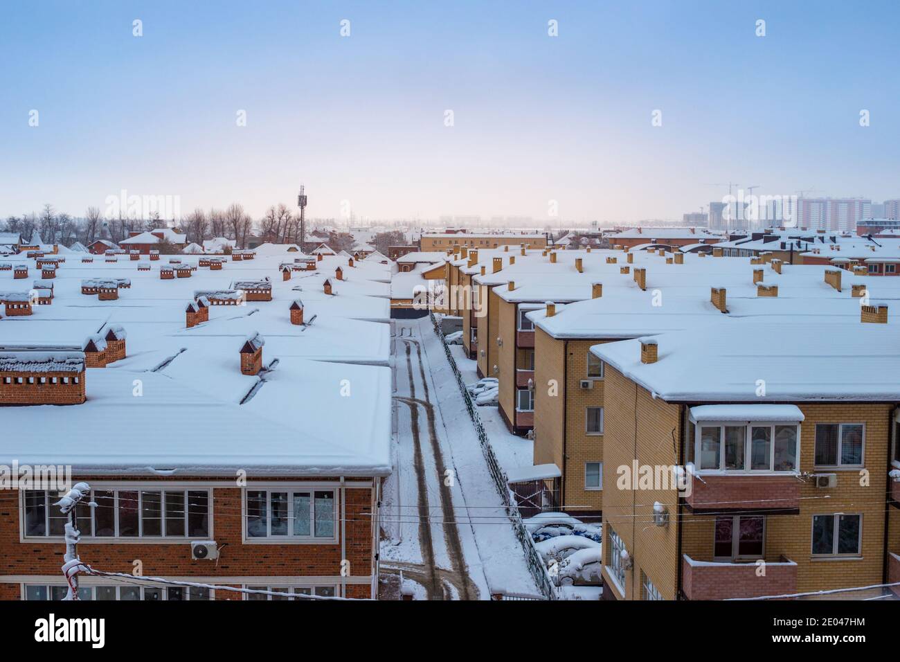 Techos cubiertos de nieve de casas en invierno. Panorama de la ciudad, vista superior. Foto de stock