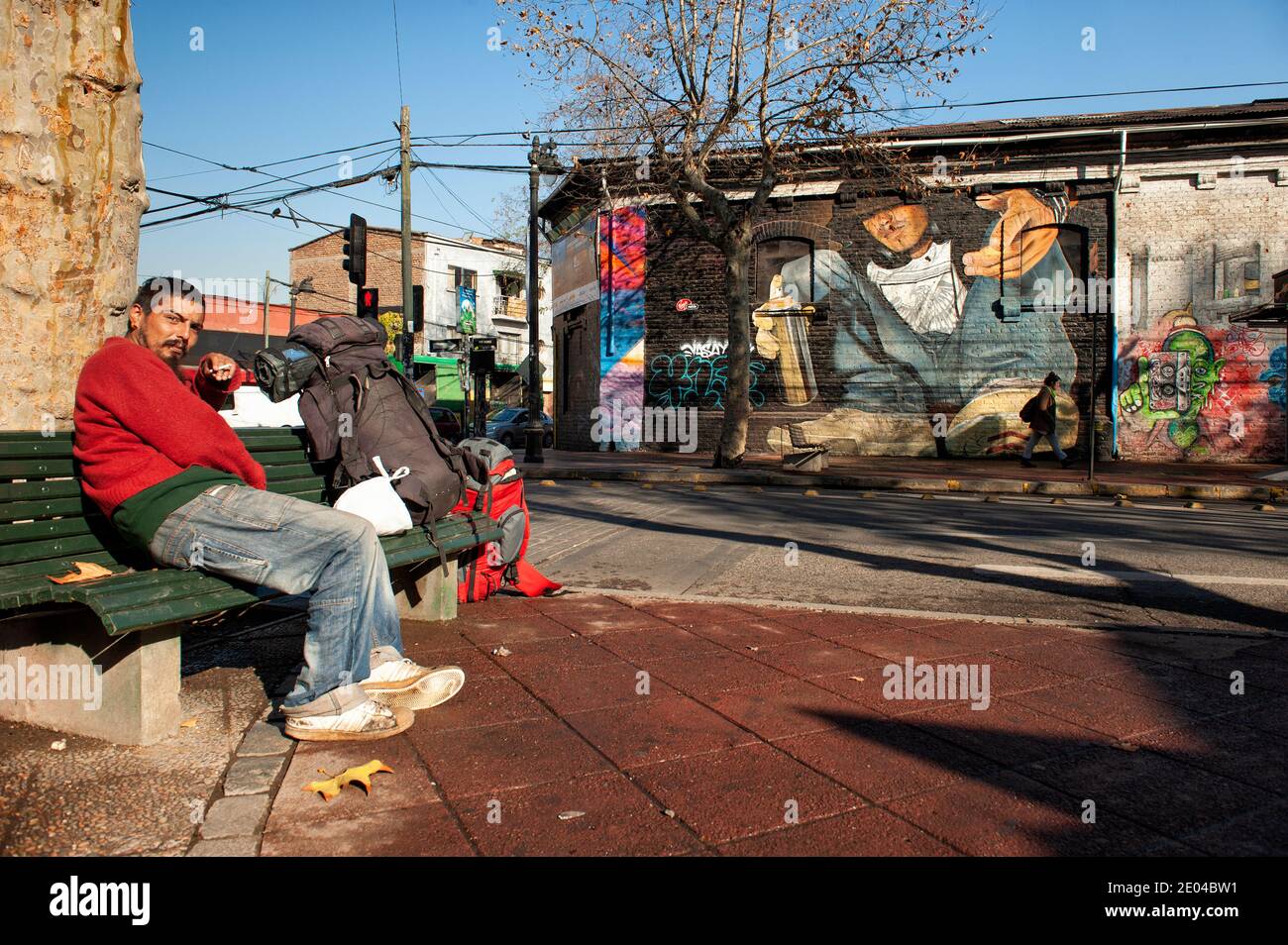 Sin hogar en la calle de Santiago de Chile, con graffiti de arte callejero detrás. Foto de stock