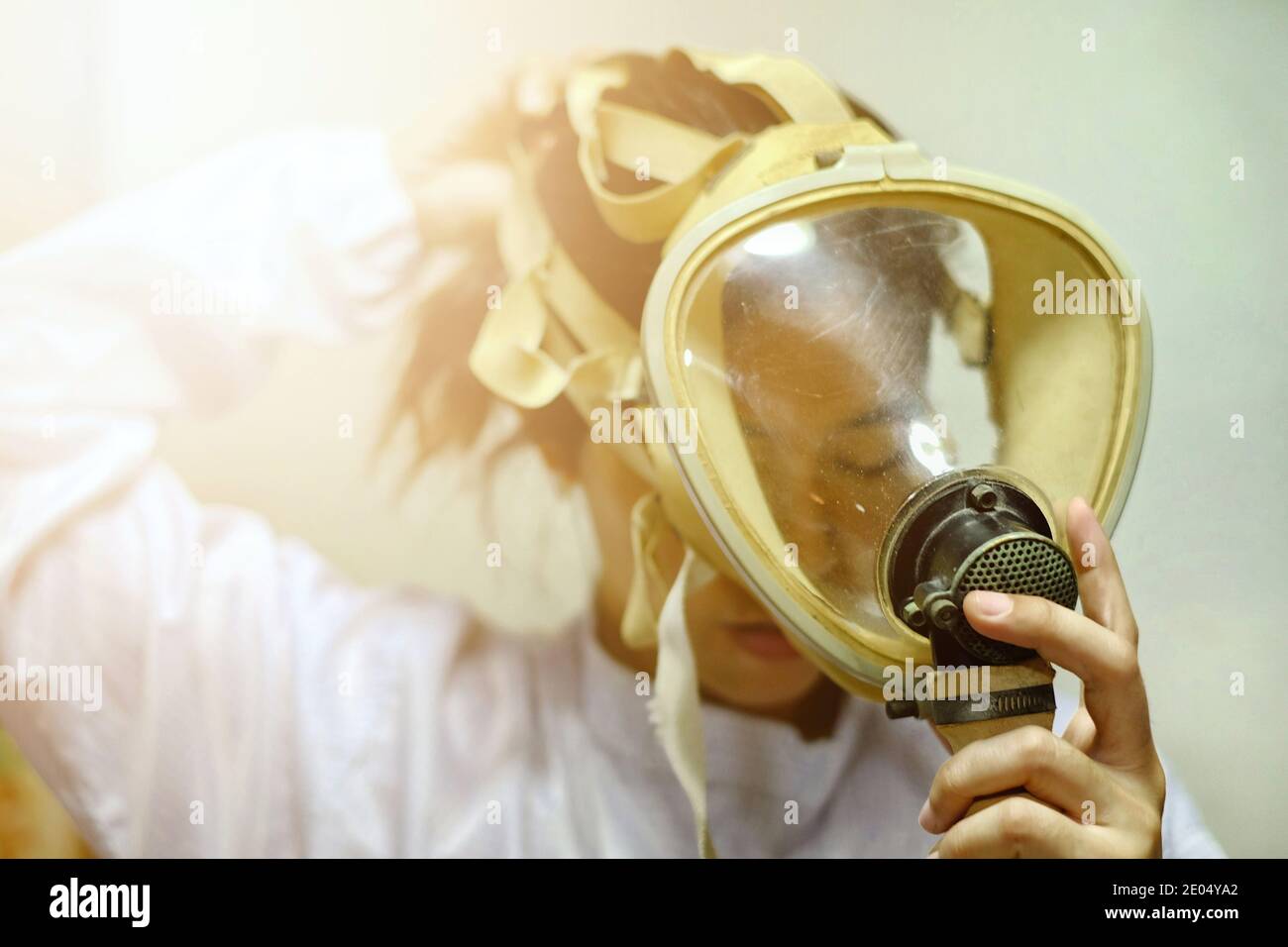 Una mujer asiática que tira de una máscara de oxígeno protector de cara completa, abrigo blanco y guantes de goma, preparándose para trabajar en un laboratorio bioquímico. Foto de stock