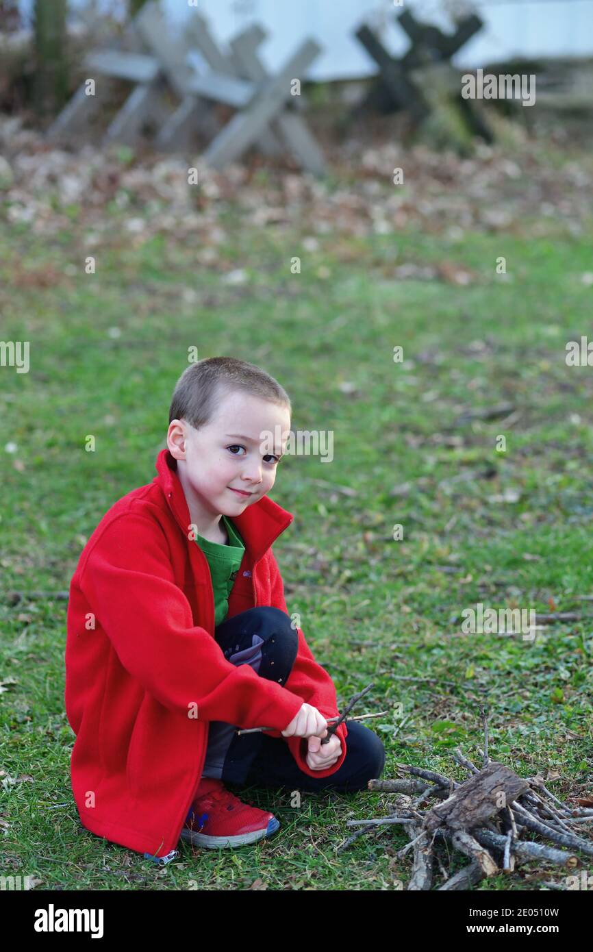 West Chicago, Illinois, EE.UU. Un niño pequeño, con una chaqueta ligera el calor en un fresco día de otoño, frota palos juntos pretendiendo un fuego Fotografía de stock - Alamy