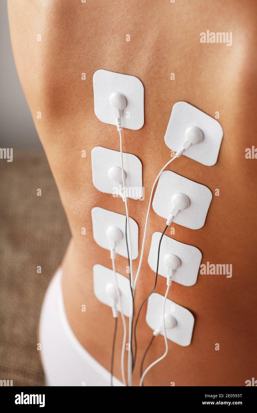 Masaje de espalda y hombros con un estimulador muscular con electrodos a lo  largo de la columna vertebral. Rehabilitación y tratamiento, pérdida de  peso Fotografía de stock - Alamy