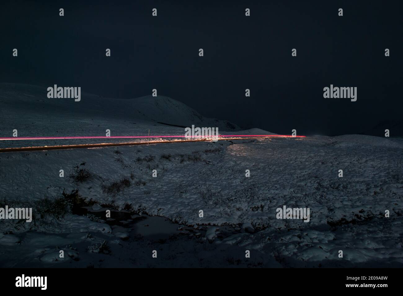 Glencoe, Escocia, Reino Unido. 30 de diciembre de 2020. En la foto: El A82 visto con un vehículo solitario por la noche bajo la luna de caída. La nieve refleja la luz causando una imagen nocturna dramática. La nieve amarilla advierte en su lugar como más nieve con temperaturas de congelación se espera de nuevo durante la noche. Crédito: Colin Fisher/Alamy Live News Foto de stock