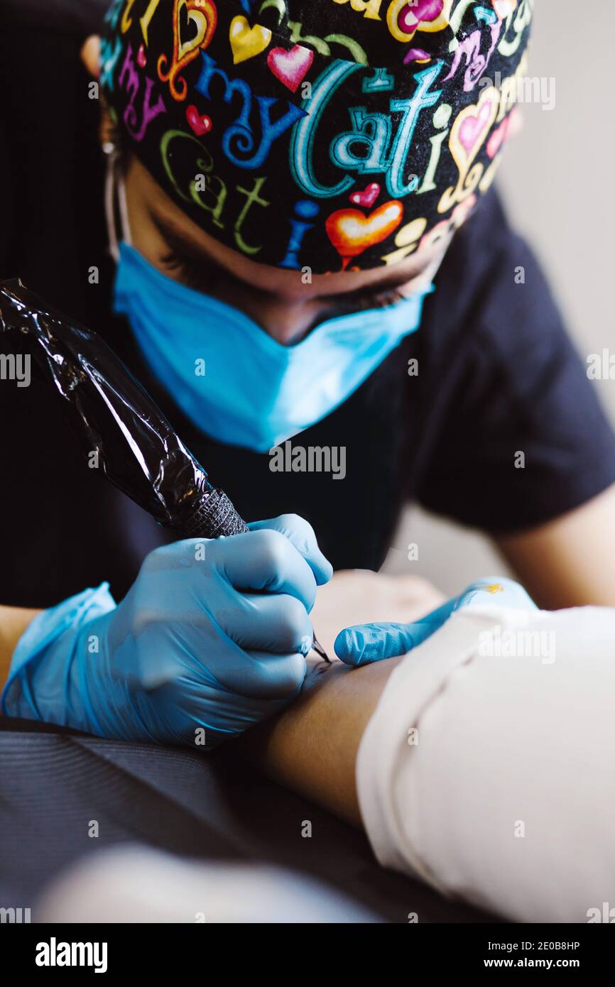 Mujer latina tatuaje artista demuestra el proceso de conseguir tatuaje Con  pintura y trabajos en guantes azules estériles en México ciudad Fotografía  de stock - Alamy