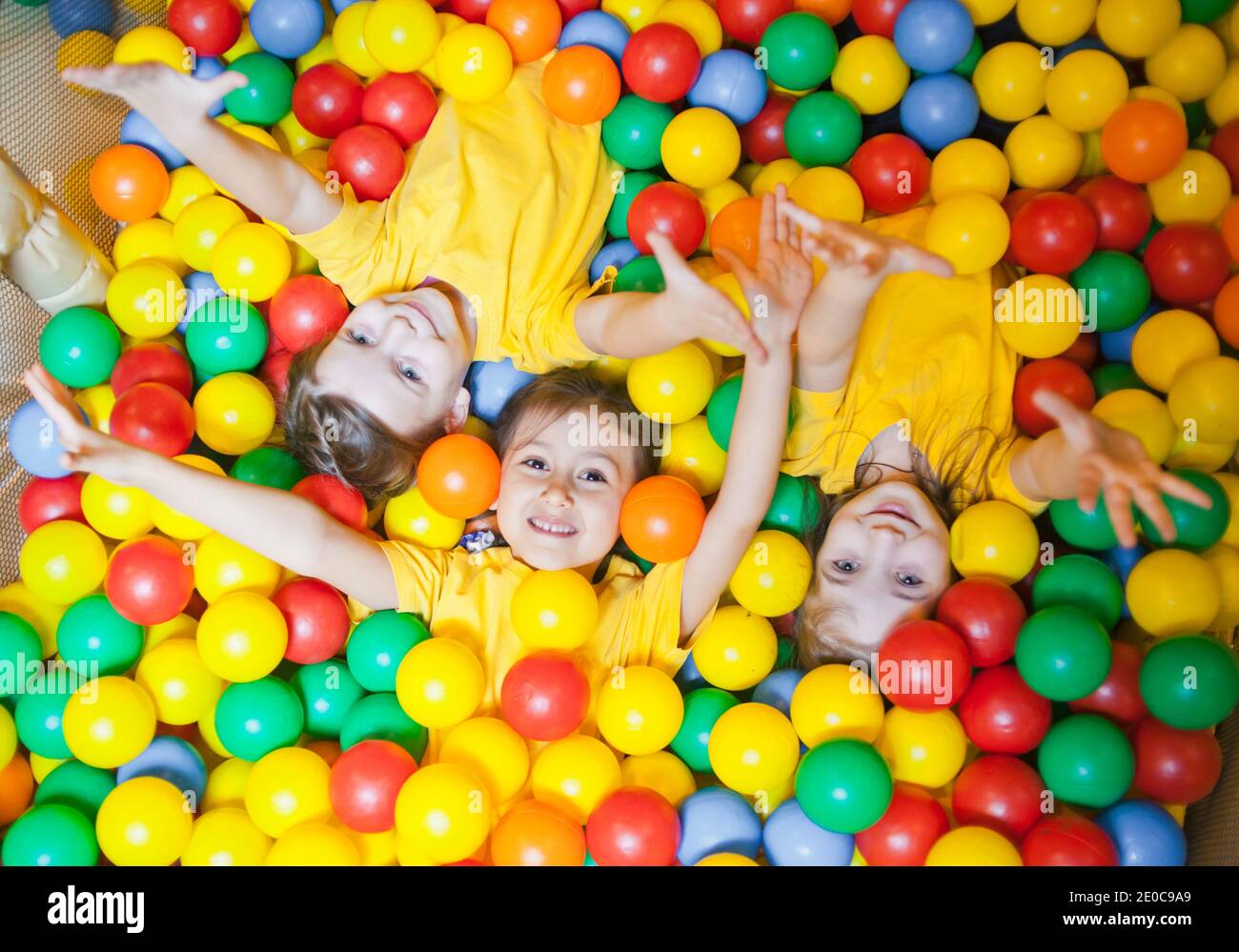 Tres niñas felices niños en el hoyo de pelota sonriendo felizmente en la cámara mientras se divierten el centro de juegos para Vista superior de stock - Alamy