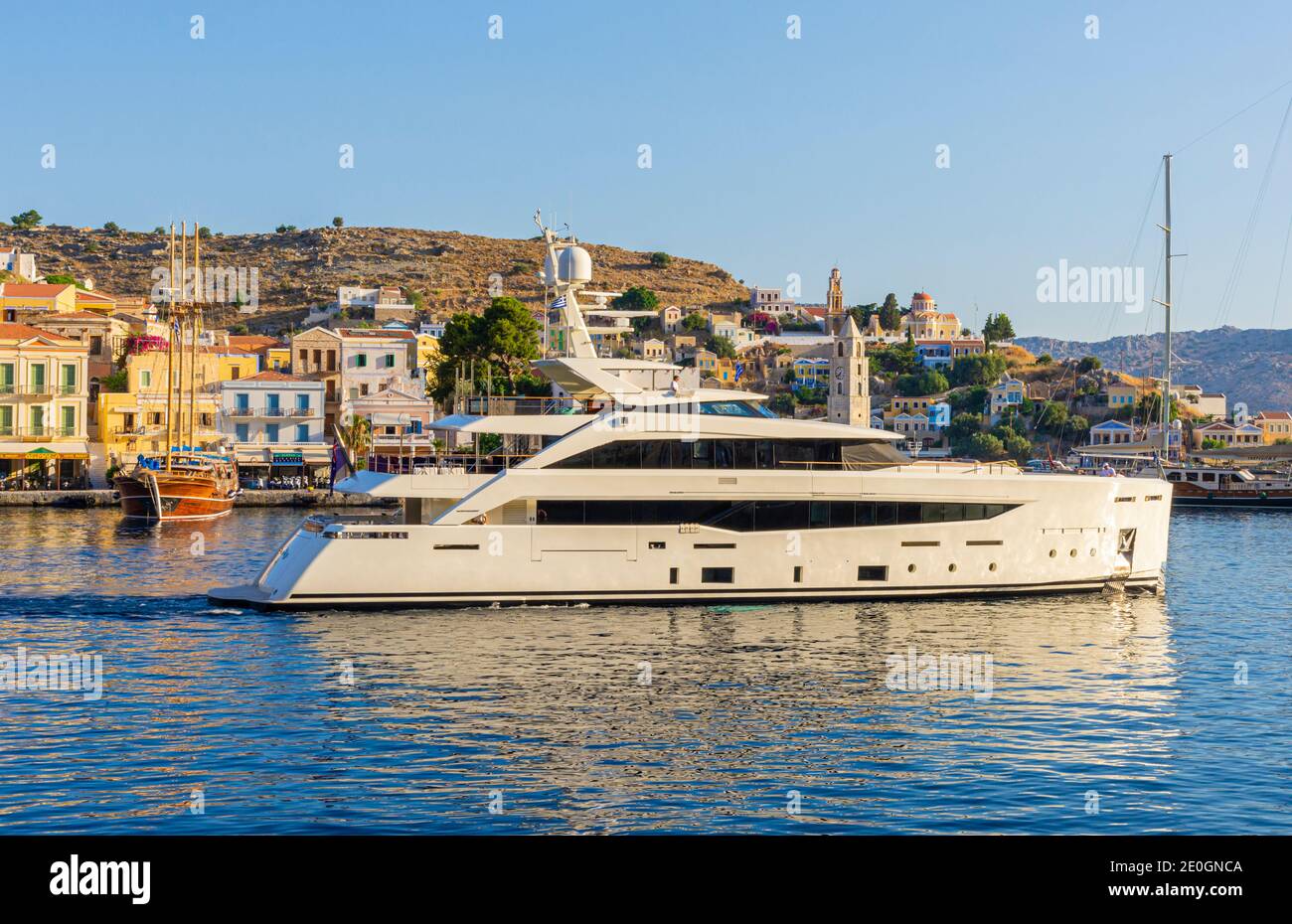 El superyate Serenity sale del puerto de Gialos, isla de Symi, Grecia Foto de stock