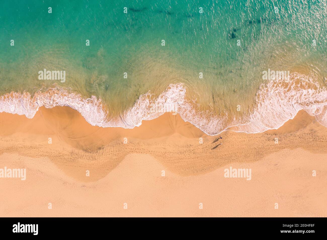 Vista aérea de arriba hacia abajo de la hermosa costa del océano Atlántico con aguas cristalinas color turquesa y playa de arena, olas que ruinan en la costa Foto de stock