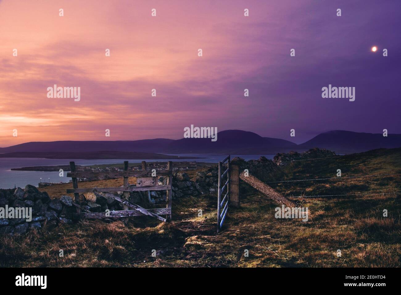 Cielo púrpura durante el amanecer sobre la ciudad escocesa Stromness en Orkney islas con puerta abierta Foto de stock
