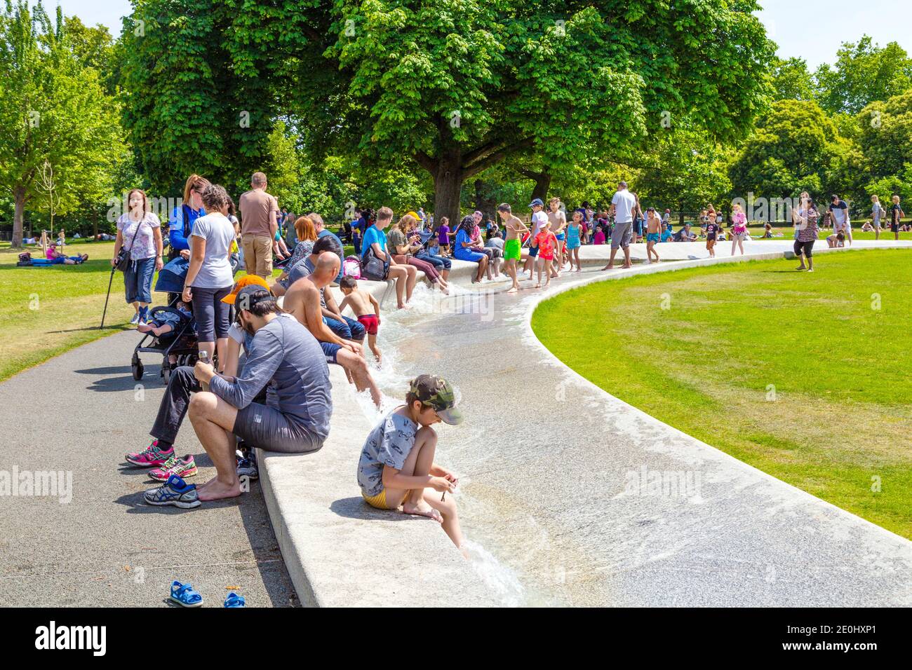 Niños y familias chapoteando en la Fuente Memorial de la Princesa Diana en un caluroso día de verano, Hyde Park, Londres, Reino Unido Foto de stock