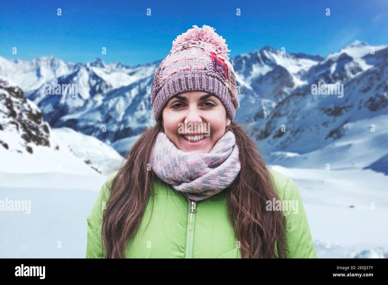 Mujer joven retrato de invierno con ropa cálida contra la montaña nevada. Actividad deportiva en la naturaleza y espacio vacío. Foto de stock
