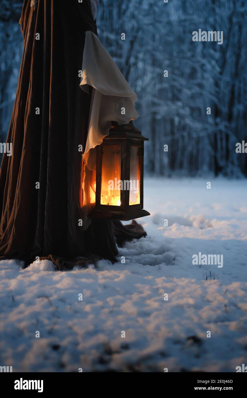 Ángulo bajo de linterna de época hermosa en las manos de cosplaying mujer  con capa medieval en el bosque de invierno nocturno Fotografía de stock -  Alamy