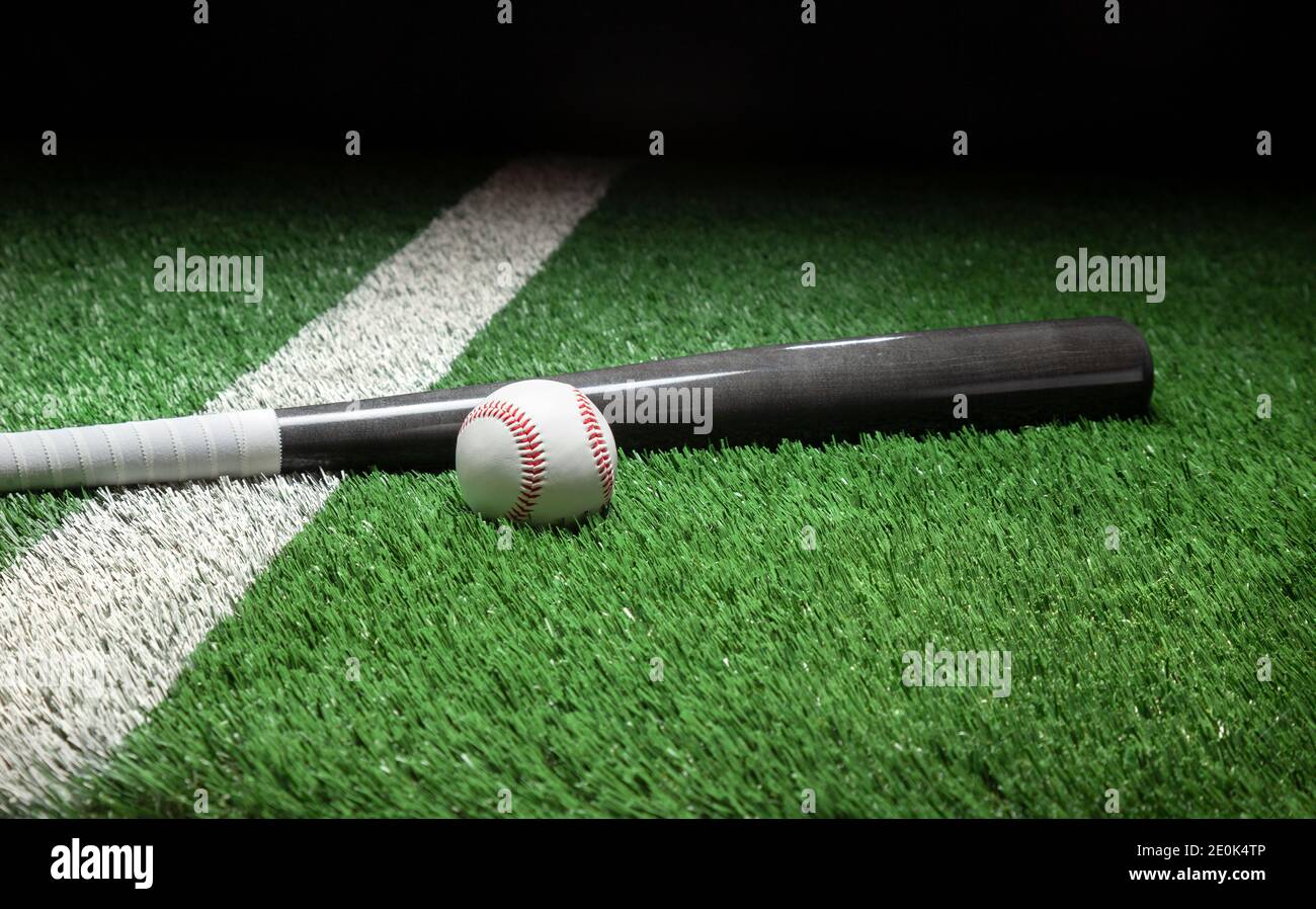 Béisbol y murciélago gris en el campo con rayas y oscuras antecedentes Foto de stock