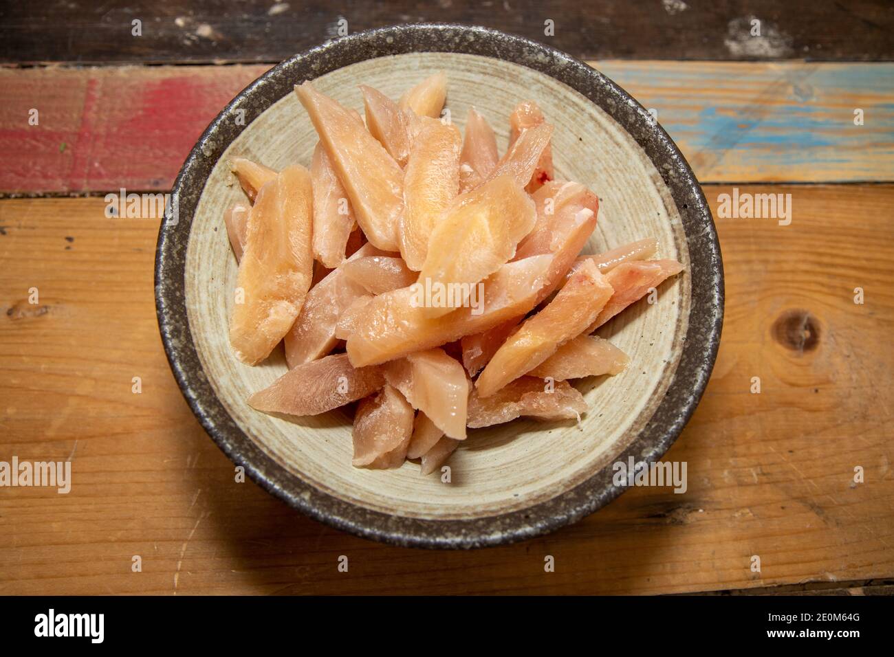 Un cuenco de trozos de pollo congelado sobre una madera encimera de cocina  lista para cocinar Fotografía de stock - Alamy