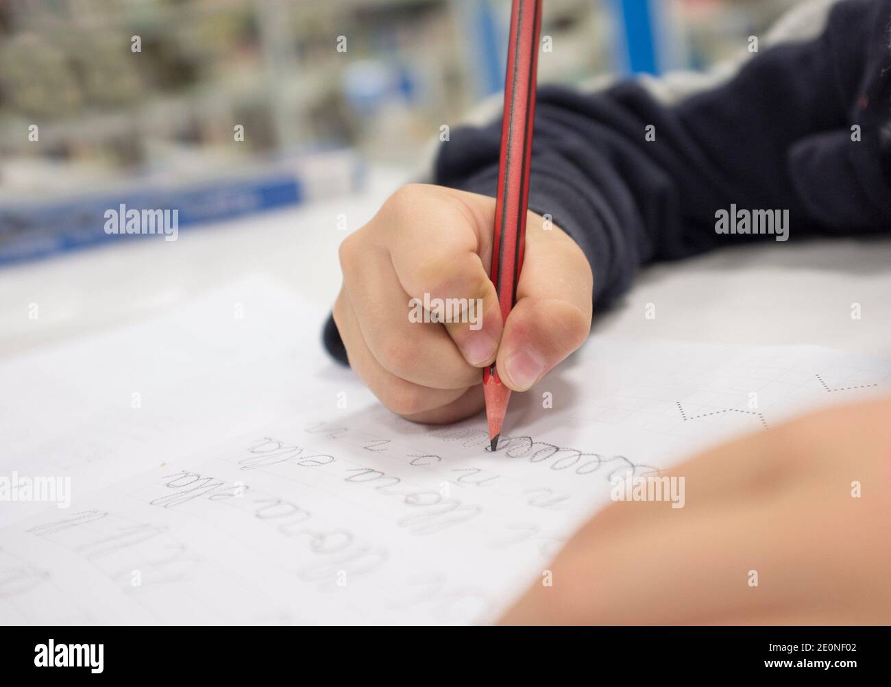 Niño pre-escritor haciendo ejercicios de caligrafía con folletos. Enfoque selectivo. Foto de stock